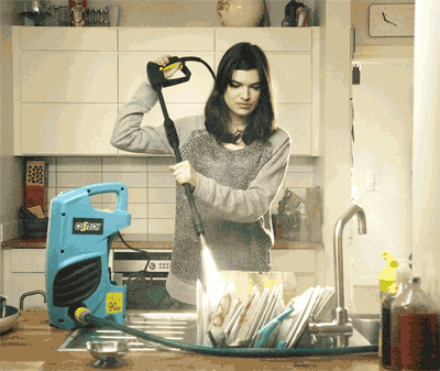 Chica usando hidrolimpiadora lanza maquina a presion para limpiar los platos en el fregadero darcerapulircera.com